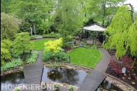 Tuin met grote vijver, gazon, veel groen en zithoek met prieel