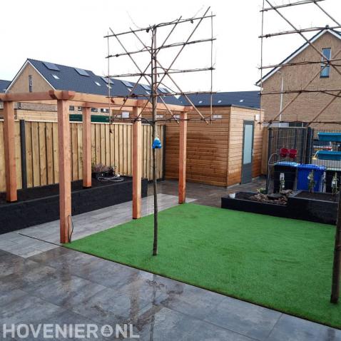 Tuinaanleg met bestrating, kunstgras, houten pergola en leibomen