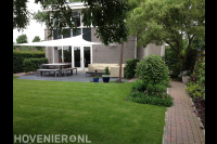 Achtertuin met gazon, terras en schaduwdoek