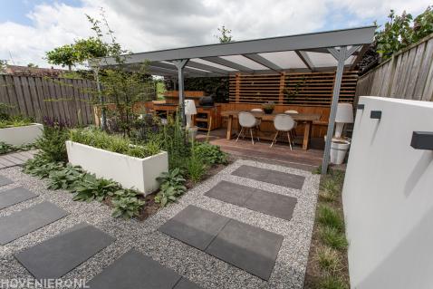 Moderne tuin met bestrating, overkapping en witte bloembakken