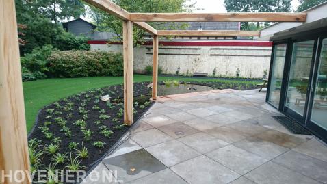 Tuin met gazon, vijver en robuuste houten pergola bij terras 1