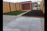 Tuinaanleg met sierbestrating, gazon, houten pergola en schutting