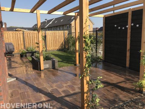 Tuinaanleg met bestrating, houten pergola, gazon en plantenbakken