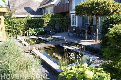 Terras met tuinset bij strakke vijver met overloop