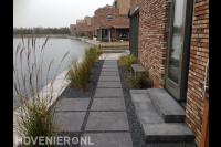 Looppad van grote tuintegels en split naar vlonder langs het water