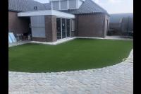 Achtertuin met kunstgras en bestrating met kasseien 1