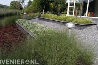 Onderhoudsarme tuin met siergrassen en split aan het water