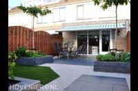 Strakke tuin met terras, gazon, plantenbakken en houten schutting 1