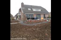 Voorbereidend grondwerk in tuin bij villa met verhoogd terras