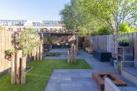 Loungetuin met sierbestrating, kunstgras en houten overkapping