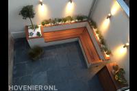 Bestrating van natuursteen en combinatie van bank en plantenbak