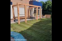 Achtertuin met gazon van graszoden en houten pergola met schommel