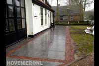 Bestrating van grote natuurstenen tegels met accenten van waaltjes