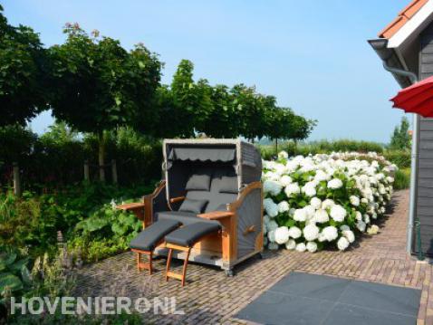 Tuin met luxe ligbank en grote witte hortensia's