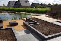 Tuin aan het water met bestrating, verhoogde borders en houten vlonder