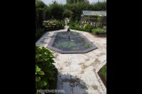 Bestrating met lichte siertegels rondom vijver afgedekt met betongaas