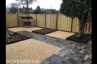 Tuinaanleg met sierbestrating, grind en houten schutting