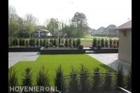 Moderne achtertuin met grote tegels, kunstgras en verhoogde borders