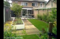 Moderne tuin met terras, kunstgras, vlonder en witte plantenbak
