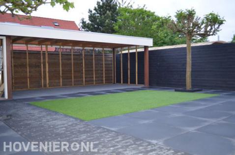 Moderne tuin met grote tegels, kunstgras en houten overkapping 1