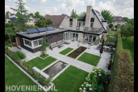 Moderne tuin met vijver, gras en lichte bestrating van grote tegels