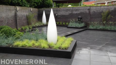 Moderne tuin met strakke bestrating en bijzondere witte lampen