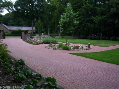 Tuin met groot gazon en oprit van rode betonklinkers