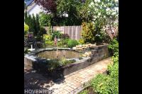 Kleine ronde vijver met waterloop bij terras