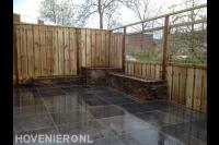 Bestrating van natuursteen, houten schutting en plantenbakken