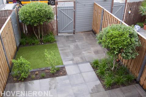 Kleine achtertuin met natuursteen tegels en hout beton schutting
