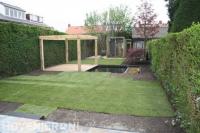 Tuinaanleg met graszoden en houten vlonder met pergola bij vijver