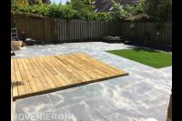 Achtertuin met betontegels, houten vlonder en kunstgras