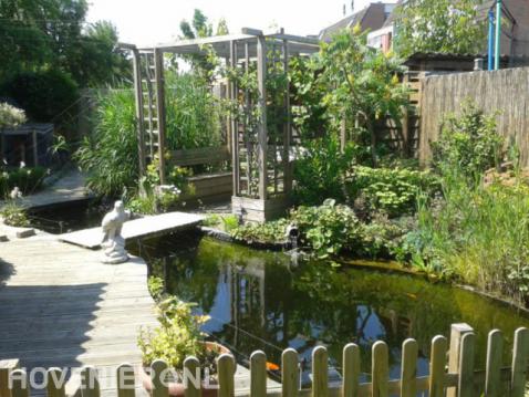 Tuin met vijver en houten vlonder en pergola