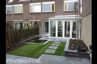 Strakke tuin met sierbestrating, gazon van graszoden en vijver