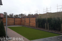 Tuinaanleg met bestrating, schutting, kunstgras en leibomen