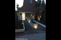 Moderne tuin met witte bloembakken, borders en overkapping met berging