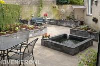 Achtertuin met plantenbakken van stapelblokken en kleine vijver