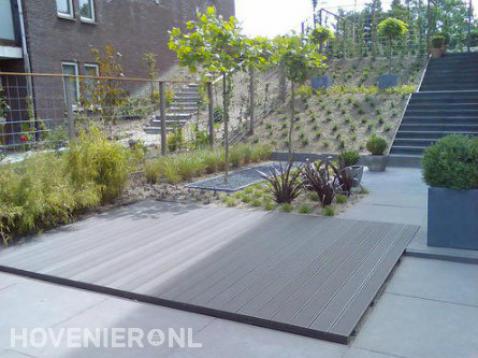 Tuin met hoogteverschil, trap, bestrating en houten vlonder