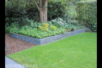 Achtertuin met grasmat, plantenbakken en houtsnippers