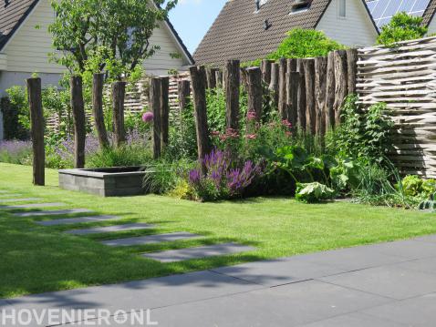 Gazon met stapstenen en vijver omgeven door houten palen