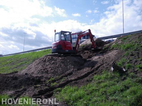 Grondwerk met minigraver langs snelweg