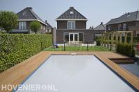 Kindvriendelijke tuin met kunstgras en pergola en vlonder bij zwembad