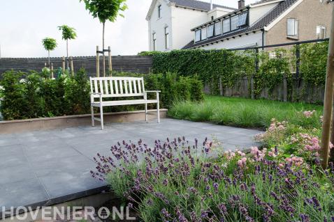 Moderne tuin met veel groen en terras van betontegels 2