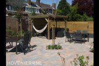 Tuinaanleg met bestrating, houten overkapping en schutting