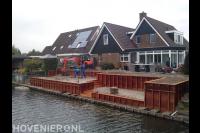 Tuin met hoogteverschillen en houten beschoeiing langs het water