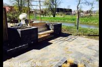 Loungetuin met houten zitbank tussen bloembakken van stapelblokken