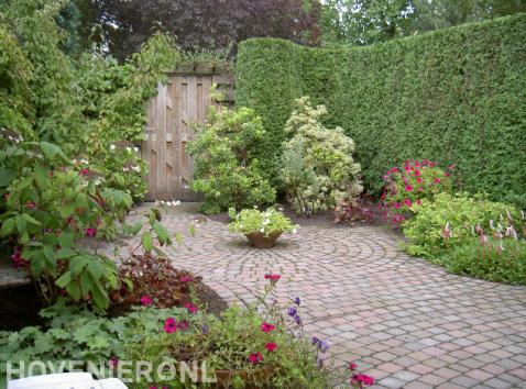 Groene tuin met kleurrijke beplanting en bestrating van koppelstenen 1