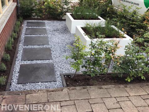 Moderne voortuin met split, witte plantenbak en beukenhaag