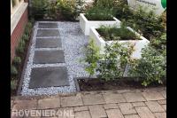 Moderne voortuin met split, witte plantenbak en beukenhaag