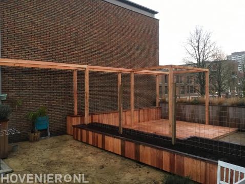 Achtertuin met houten pergola, vlonder en plantenbakken